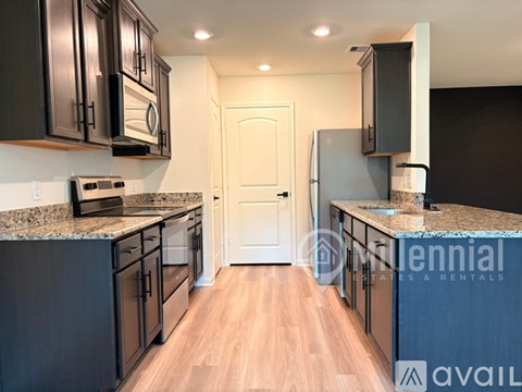 A kitchen with dark cabinets and a white door.