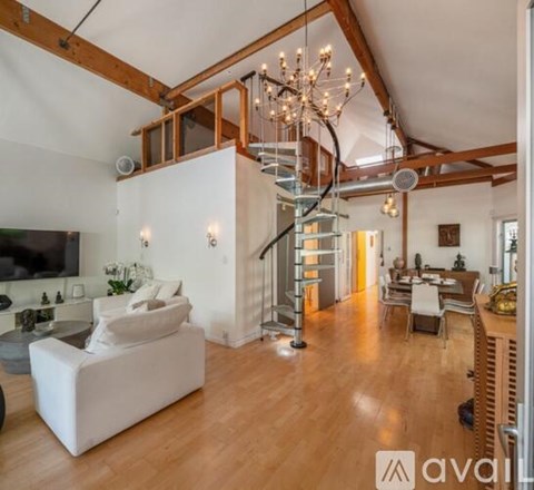 A living room with a white couch and a wooden staircase.
