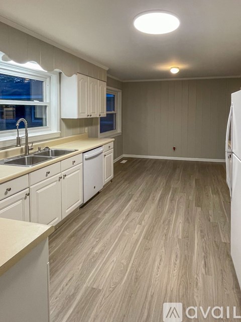 A kitchen with white cabinets and a wooden floor.