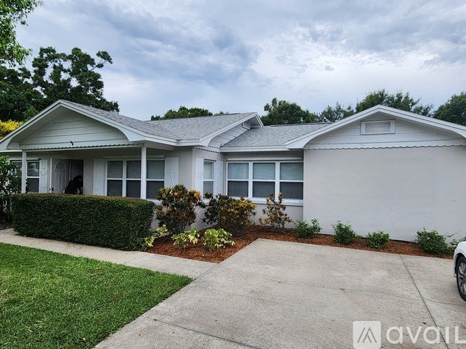 A white house with a grey roof and a grey driveway.