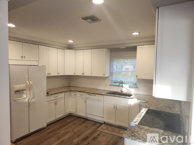 A kitchen with white cabinets and a granite countertop.