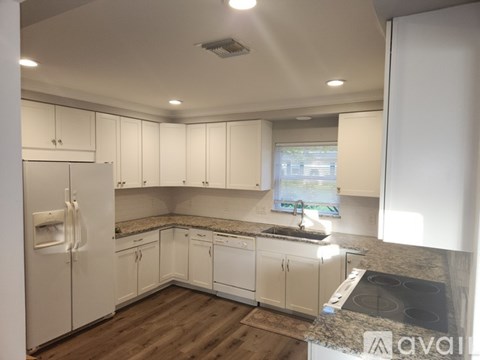 A kitchen with white cabinets and a granite countertop.