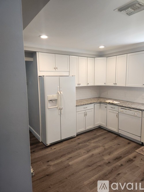 A kitchen with white cabinets and a wooden floor.