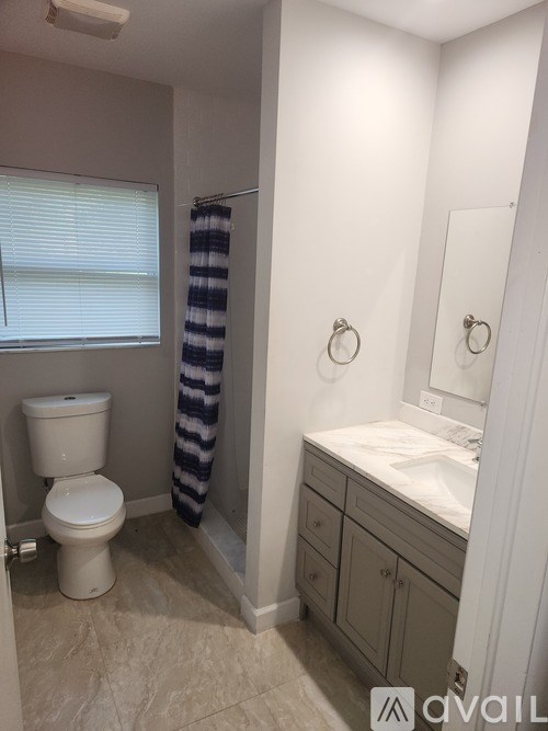 A bathroom with a toilet, sink, and a striped shower curtain.