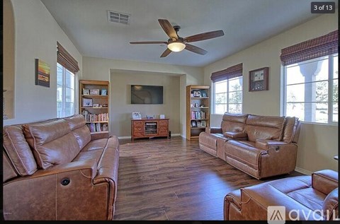 A living room with brown leather furniture and a ceiling fan.
