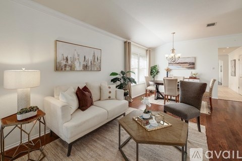 A living room with a white couch, a brown coffee table, and a painting on the wall.