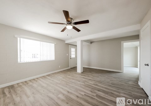 A spacious room with a ceiling fan and light wood flooring.