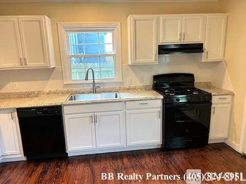 A kitchen with white cabinets and black appliances.