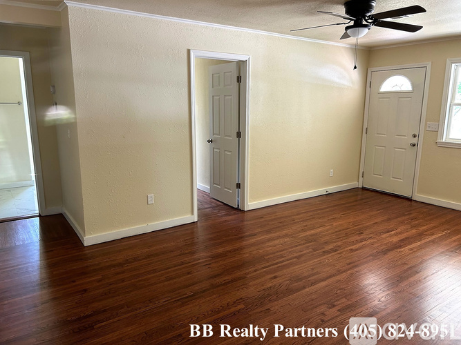 A room with a ceiling fan and wood flooring.