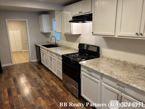 A kitchen with white cabinets and a black stove top oven.
