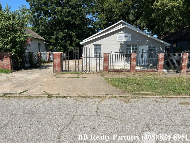 A house with a driveway and a fence in front of it.