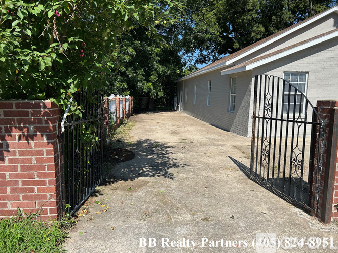 A house with a gate and a brick wall in front.