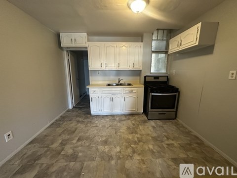 A kitchen with a white cabinetry and a tiled floor.