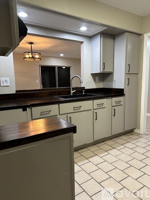 A kitchen with white cabinets and a black countertop.