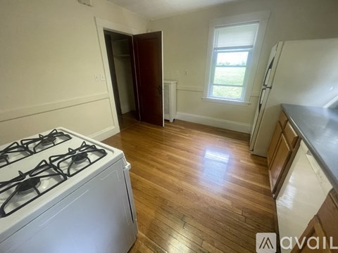 A kitchen with a white gas stove and wooden flooring.