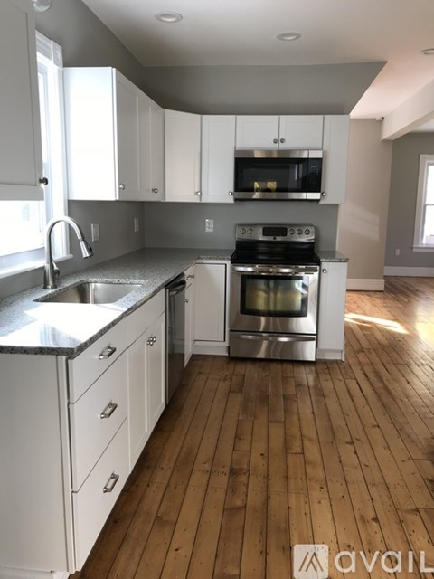 A kitchen with white cabinets and a wooden floor.