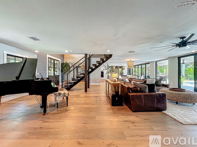 A living room with a grand piano and a staircase.