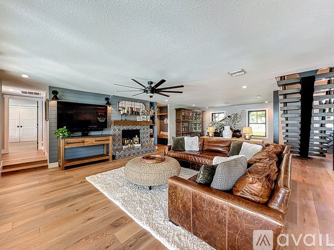 A living room with a brown leather couch and a white rug.
