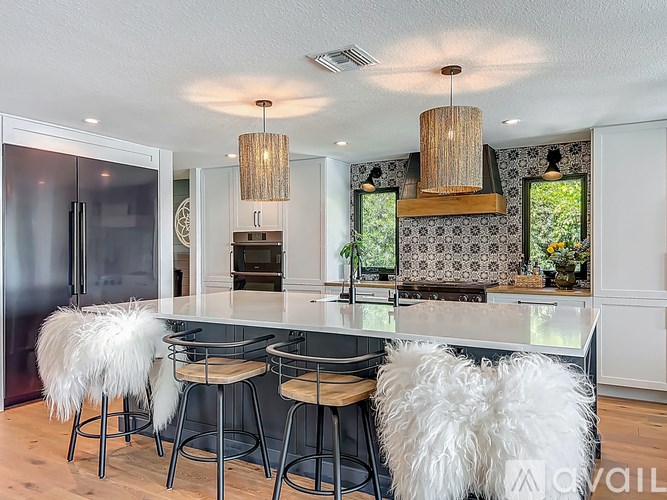 A modern kitchen with a bar area and white stools.