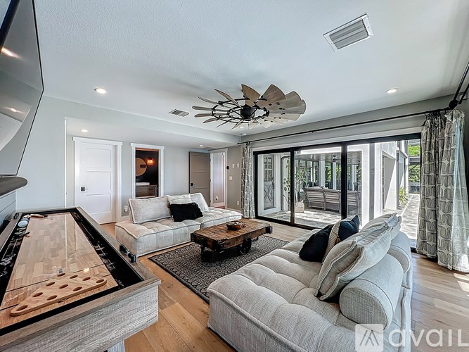 A modern living room with a pool table and a large window.