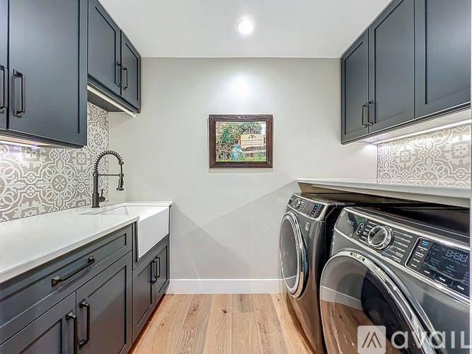 A laundry room with a washer and dryer, a sink, and cabinets.