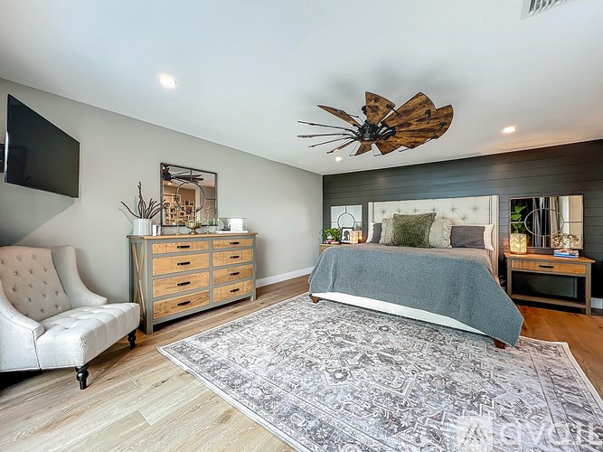 A bedroom with a large bed and a white chair.