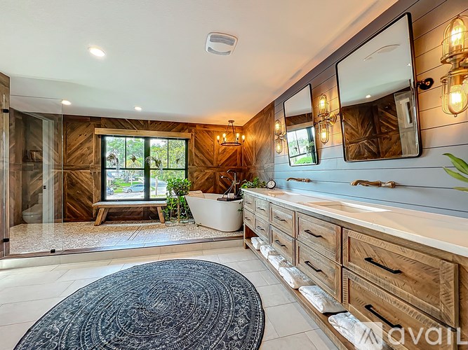 A bathroom with a large mirror, a tub, and a window.