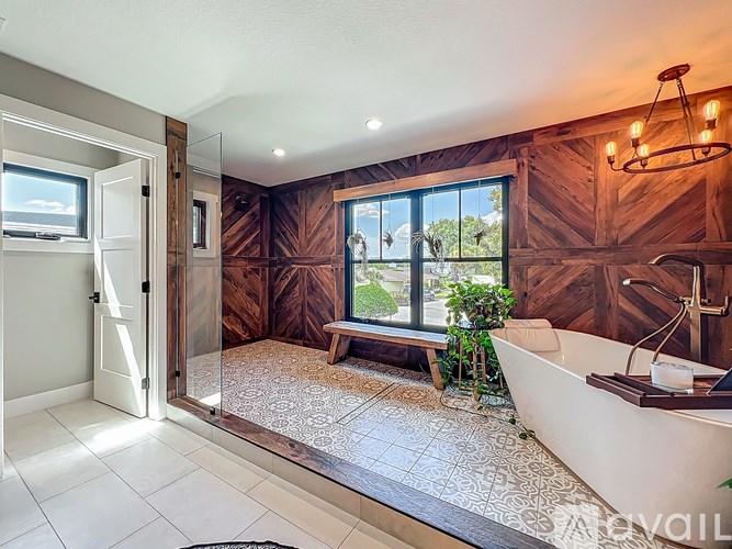 A bathroom with a tub, a window, and a wooden wall.
