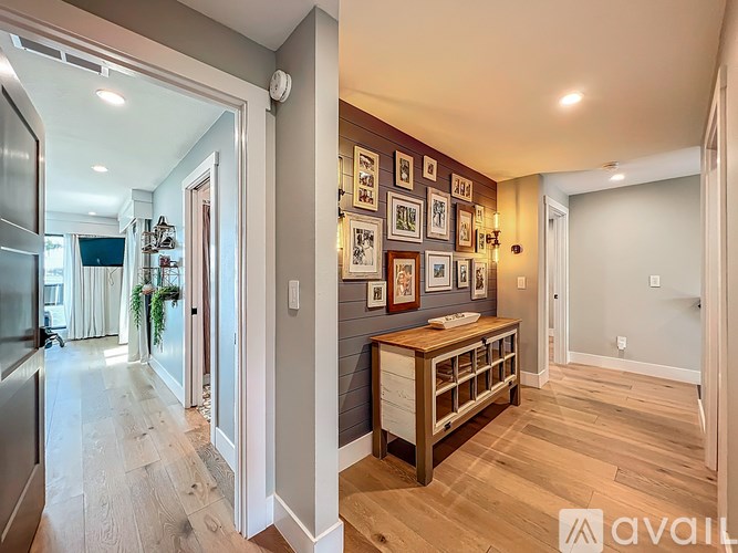 A hallway with a wooden table and framed pictures on the wall.