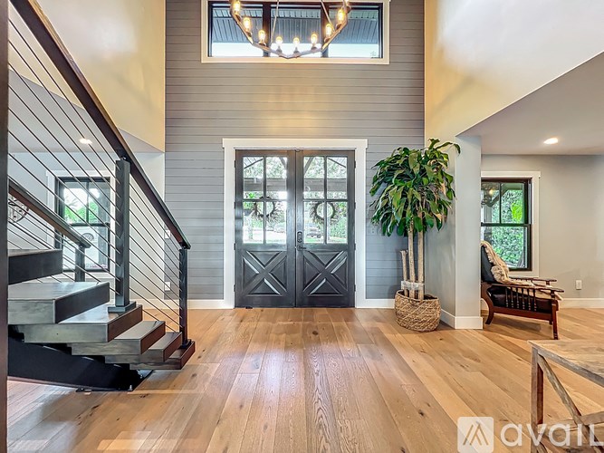 A wooden staircase with a metal railing leads to a living room with a couch and a potted plant.