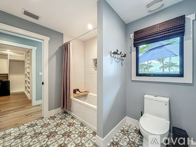 A bathroom with a toilet, a bathtub, and a window with a view of the outdoors.