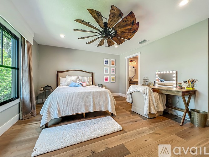 A bedroom with a bed, desk, and a ceiling fan.