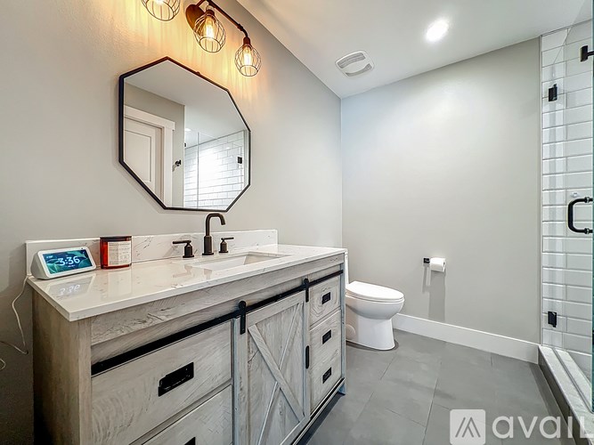 A bathroom with a mirror, sink, and toilet.