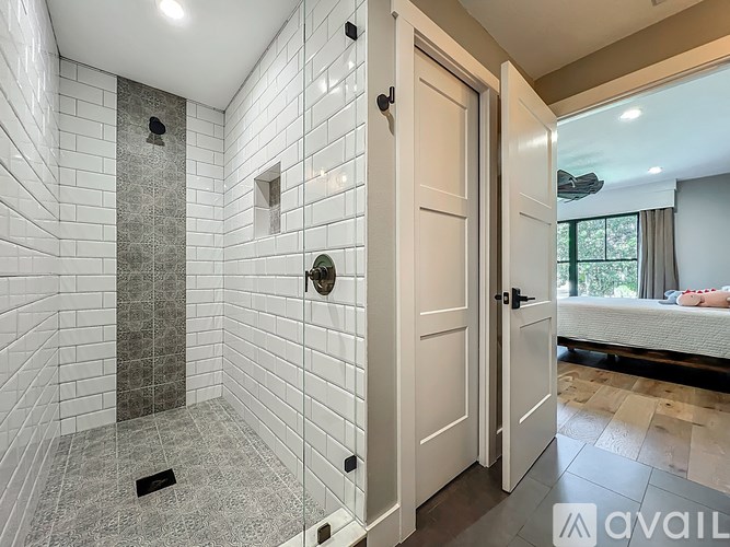 A bathroom with a walk-in shower and a white door.