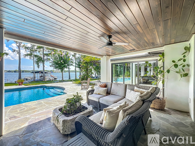 A patio with a sofa and a pool in the background.
