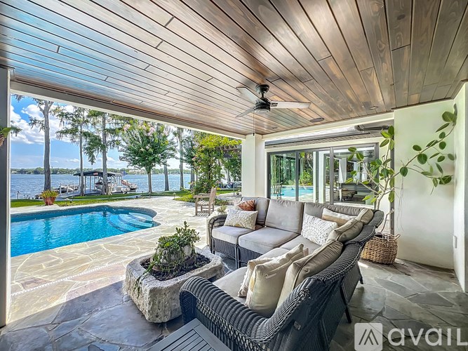 A patio with a sofa and a pool in the background.