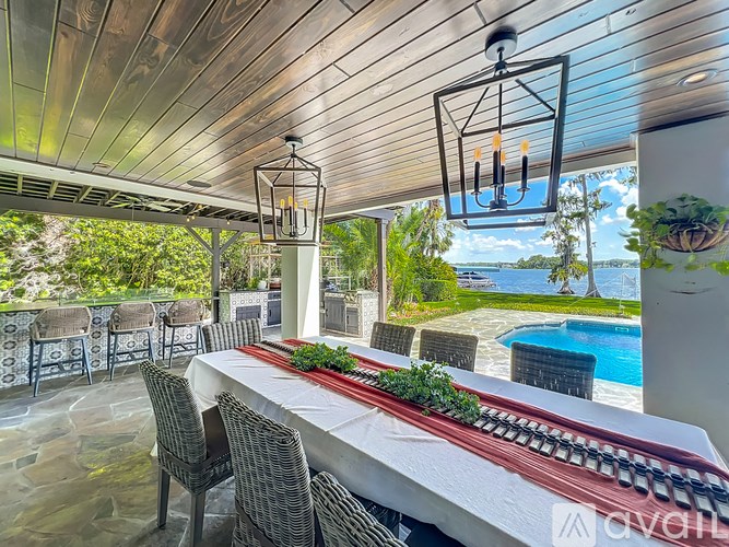 A table set for a meal with a view of the pool and trees.