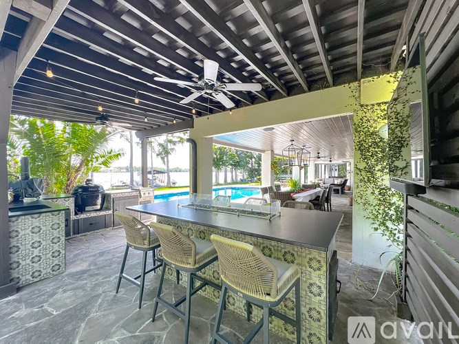 A patio with a bar and chairs overlooking a pool.