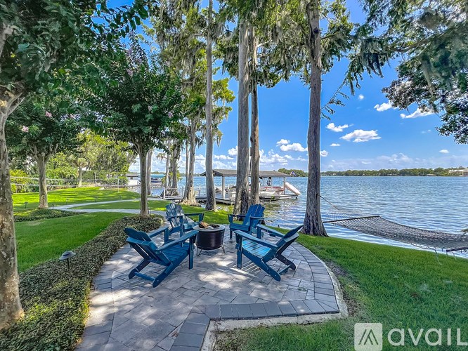 A blue bench is situated on a stone patio by a lake.