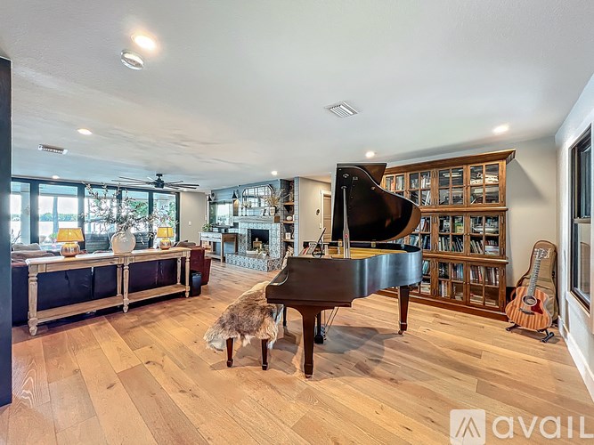 A room with a piano, a chair, and a guitar.