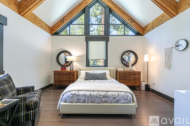 A bedroom with a large bed and a chair with a plaid pattern.
