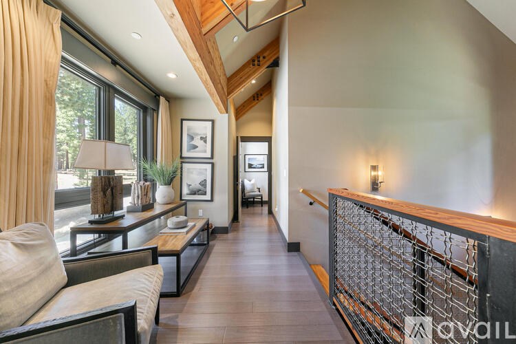 A modern living room with a wooden floor and a glass railing.