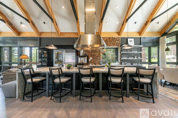 A modern kitchen with a large island and wooden beams on the ceiling.