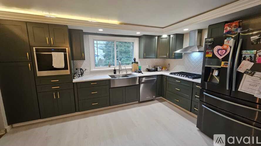 A kitchen with black cabinets and a black fridge with a white towel hanging on the microwave.
