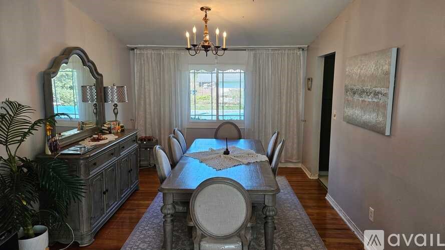 A dining room with a table set for six and a chandelier hanging from the ceiling.