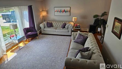 A living room with a grey sofa and a purple chair.
