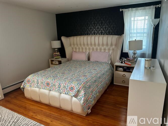 A bedroom with a patterned bedspread and a white headboard.
