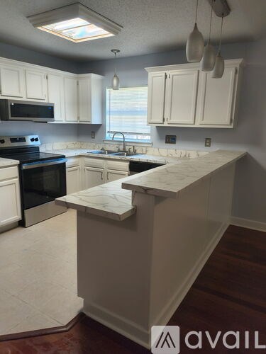 A kitchen with white cabinets and a marble countertop.