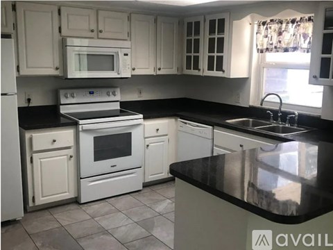 A kitchen with white cabinets and black countertops.