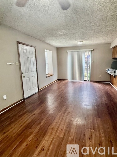 A room with wooden floors and a door on the left.